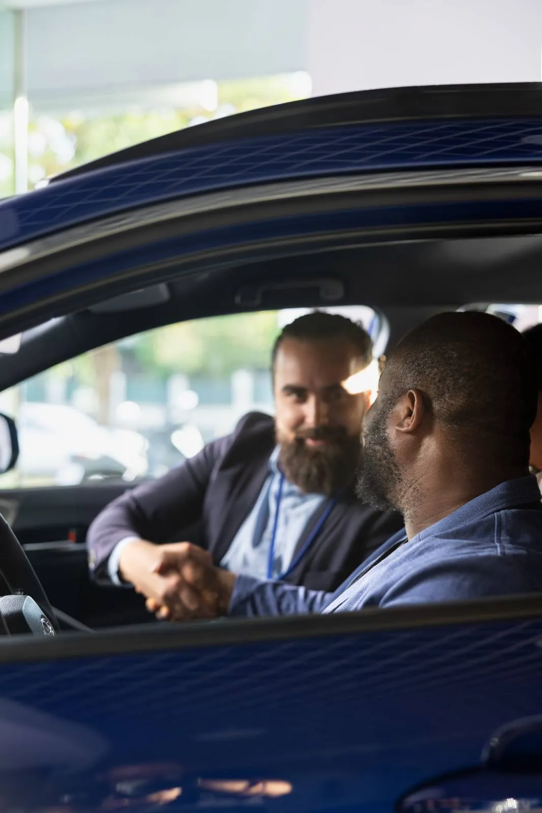 Two men shaking hands inside a car